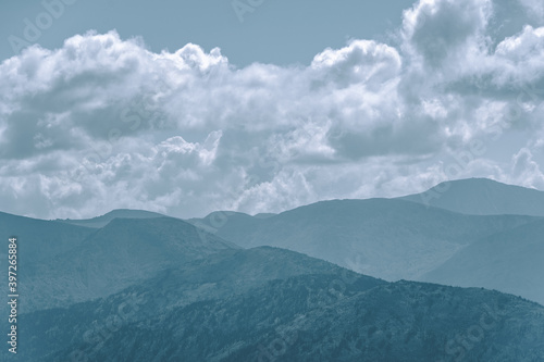 Foto Thick clouds over mountain range, hills in blue haze
