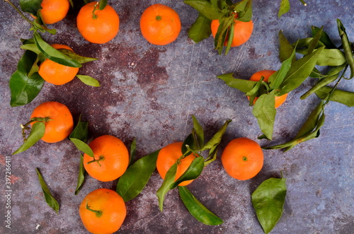 Fresh mandarin  clementine  tangerine with green leaves on a rusty surface background