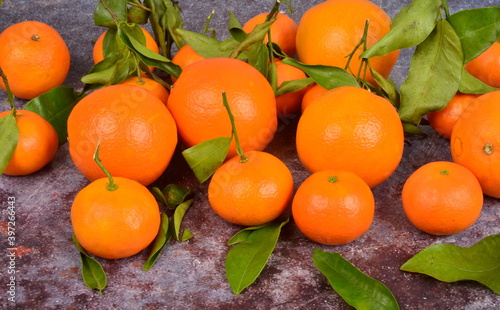 Fresh mandarin, clementine, tangerine with green leaves on a rusty surface background