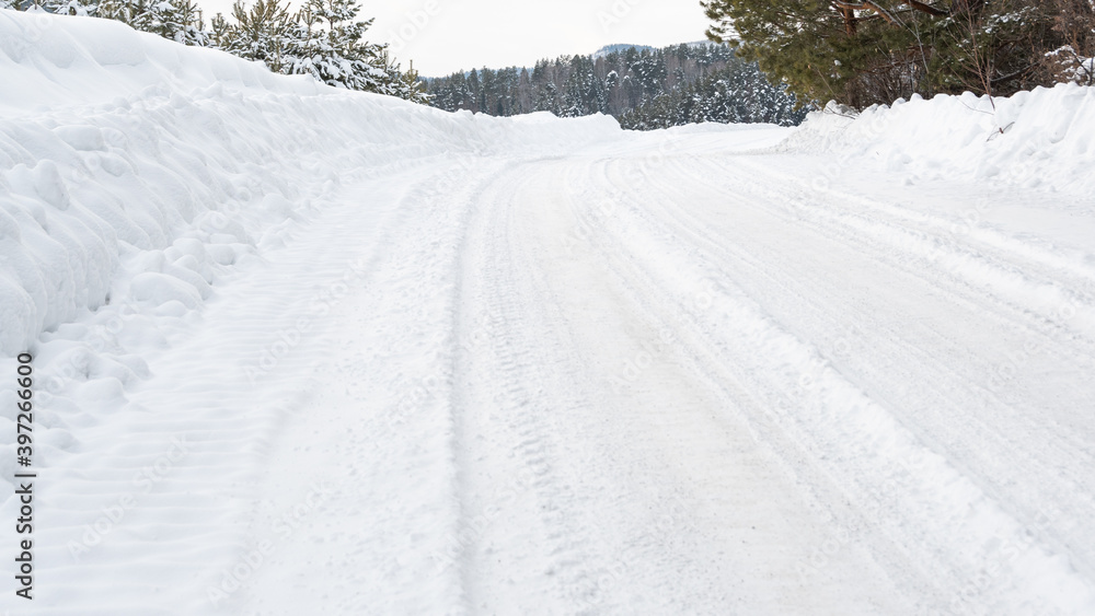Snow road in winter pine forest. Ice and snowstorm on a country road. Clearing the road from snowdrifts. Snow road in winter pine forest. Ice and snowstorm on a country road. Clearing the road from snowdrifts.