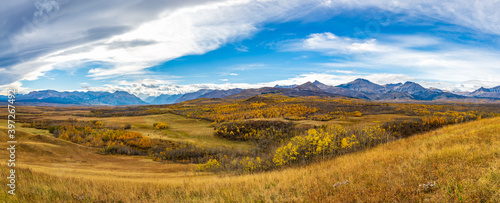 Vast prairie and forest in beautiful autumn. Sunlight passing blue sky and clouds on mountains. Fall color landscape background. Waterton Scenic Spot, Waterton Lakes National Park, Alberta, Canada. photo