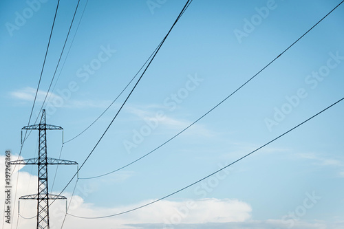 Power line tower against sky and clouds. Transmission of electricity by wire from energy company. Landscape with high voltage pylons and lines.