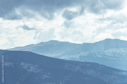 Thick clouds over mountain range, hills in blue haze