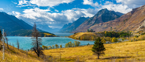 Middle Waterton Lake lakeshore in autumn foliage season sunny day morning. Blue sky, white clouds over mountains in the background. Landmarks in Waterton Lakes National Park, Alberta, Canada. photo