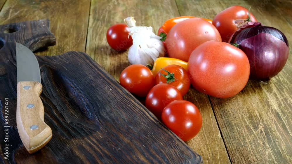 Cooks job. Different vegetables for cooking vegetarian or vegan salad throwing from paper bag onto wooden table. Kitchen knife on cooking board. Cooks job. Different vegetables for cooking vegetarian or vegan salad throwing from paper bag onto wooden table. Kitchen knife on cooking board.