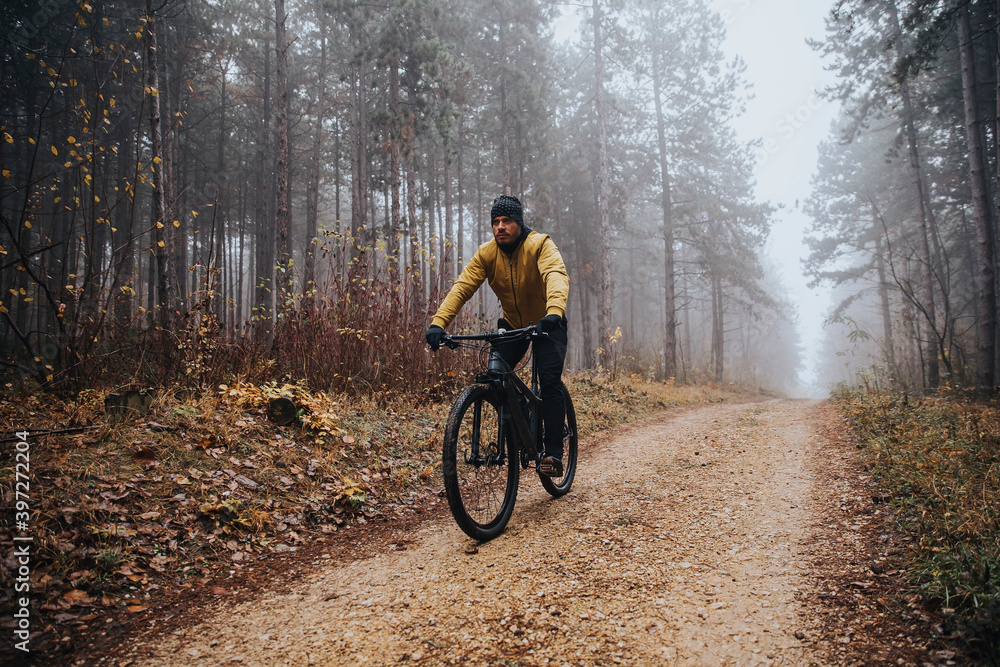 Young man biking through autumn forest