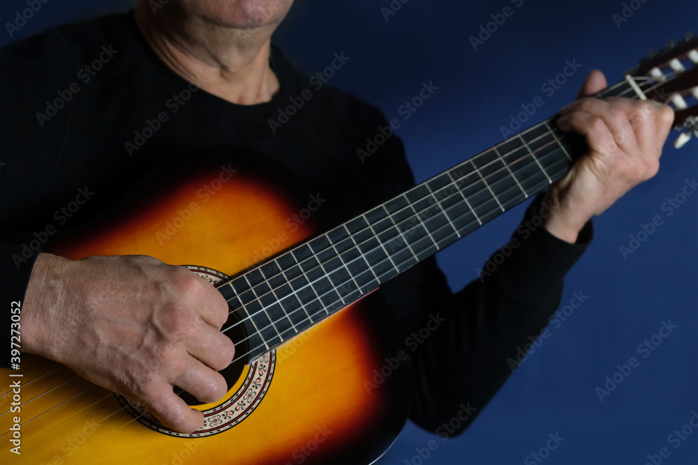 Obraz premium man plays the guitar, close-up hands, the concept of creativity, learning to play musical instruments, online learning