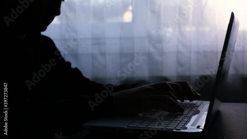 A man who opens the laptop and then works on it. Write a message. Dark image, counterpoint. Haker photo