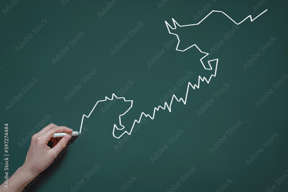 chart of stock quotes drawn in chalk on a blackboard, the concept of trading, investment and speculation, bulls and bears in the stock market, hand with chalk chart of stock quotes drawn in chalk on a blackboard, the concept of trading, investment and speculation, bulls and bears in the stock market, hand with chalk