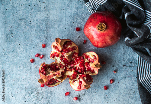 Overhead view of ripe pomegranate fruit and seeds on cement counter. photo