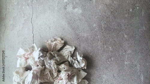 Hand takes a receipt from a store, crushes it and throws it into a pile of the same crumpled checks
