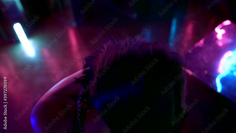 Portrait of a young woman passionately posing and dancing against walls with colorful neon lights on stage, sitting on reflective cubes. The view from the top. Portrait of a young woman passionately posing and dancing against walls with colorful neon lights on stage, sitting on reflective cubes. The view from the top.