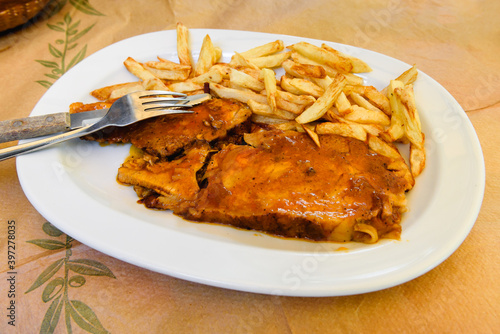 Piece of meat in sauce served with fries. Traditional Greek dish.