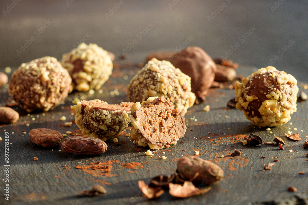 Handmade chocolates sprinkled with pistachio crumbs and cacao beans on a graphite board photographed in close-up Handmade chocolates sprinkled with pistachio crumbs and cacao beans on a graphite board photographed in close-up