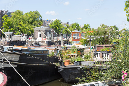 View of Amstel River in the city center of Amsterdam. Seen from Roeterseiland with canal houses, canal boats, Schutssluis.