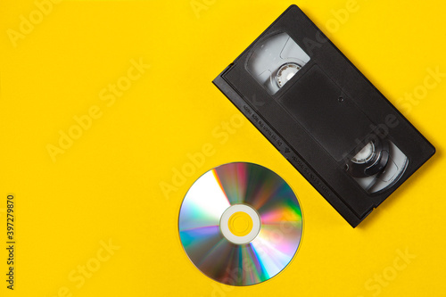 Video cassette videotape and compact disc on a yellow background. Flat lay concept.