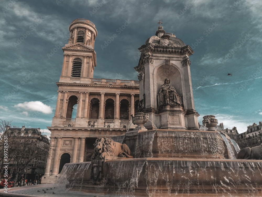 Fountain against the background of old architecture with a mysterious sky