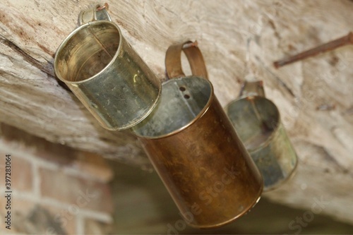 three vintage tin and copper cups hanging on wall 
