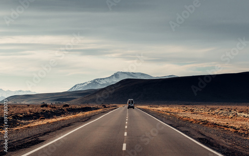 Lonely automobile going along asphalt roadway on background of amazing highlands in Patagonia photo