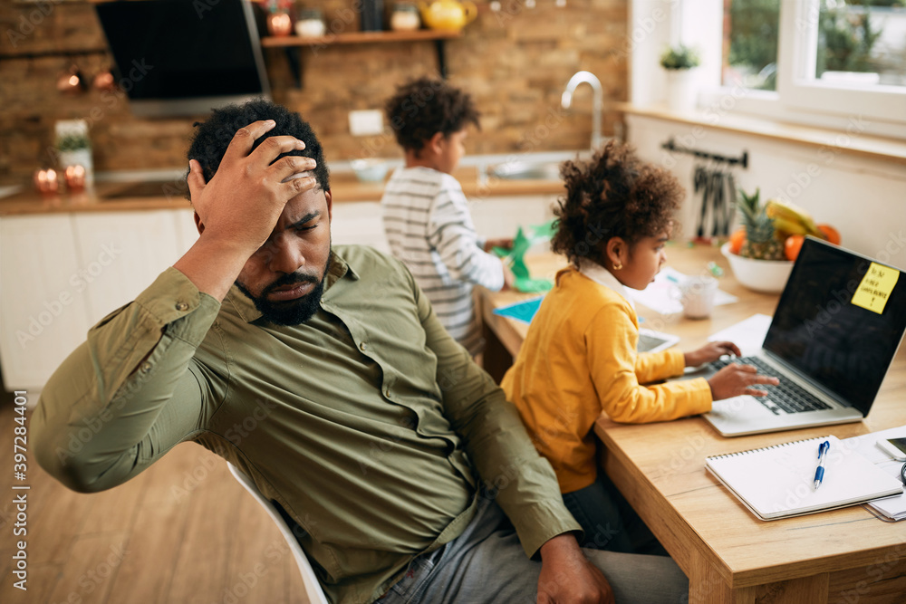 Fototapeta premium Working African American father feeling frustrated while working at home.