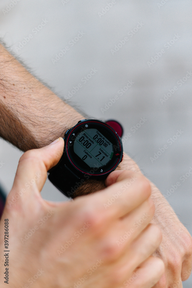 From above cropped unrecognizable athletic male checking time on wristwatch on street during training From above cropped unrecognizable athletic male checking time on wristwatch on street during training