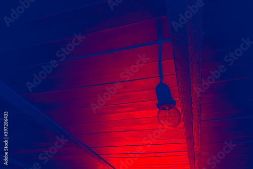 Lamp without a chandelier hangs under the ceiling. Red blue tone.