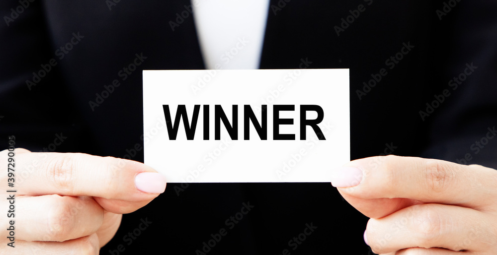 The businessman holds a card with the text WINNER in front of him. The businessman holds a card with the text WINNER in front of him.