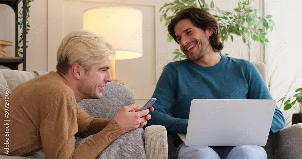 Gay couple having fun using mobile phone and laptop at home Gay couple having fun using mobile phone and laptop at home