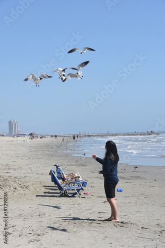 Teenage girl feeding seagulls on Galveston Island Beach, Texas
