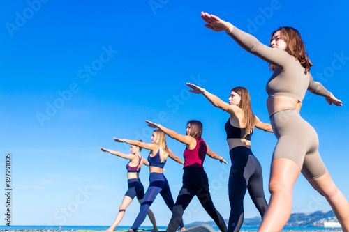 unity group of women practic yoga on rhe beach in morning