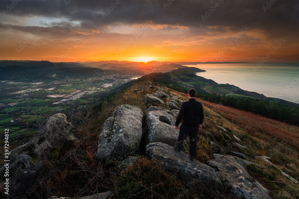 Hiker looking at the sunset from the top of Jaizkibel mountain, Basque Country.