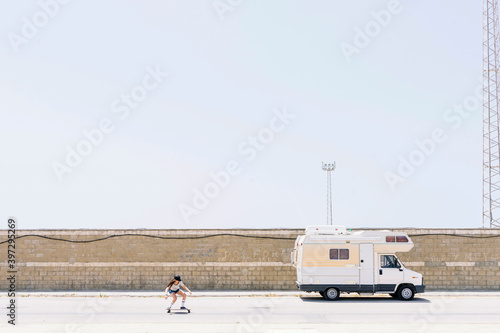 Young woman skateboarding on road against clear sky during sunny day photo