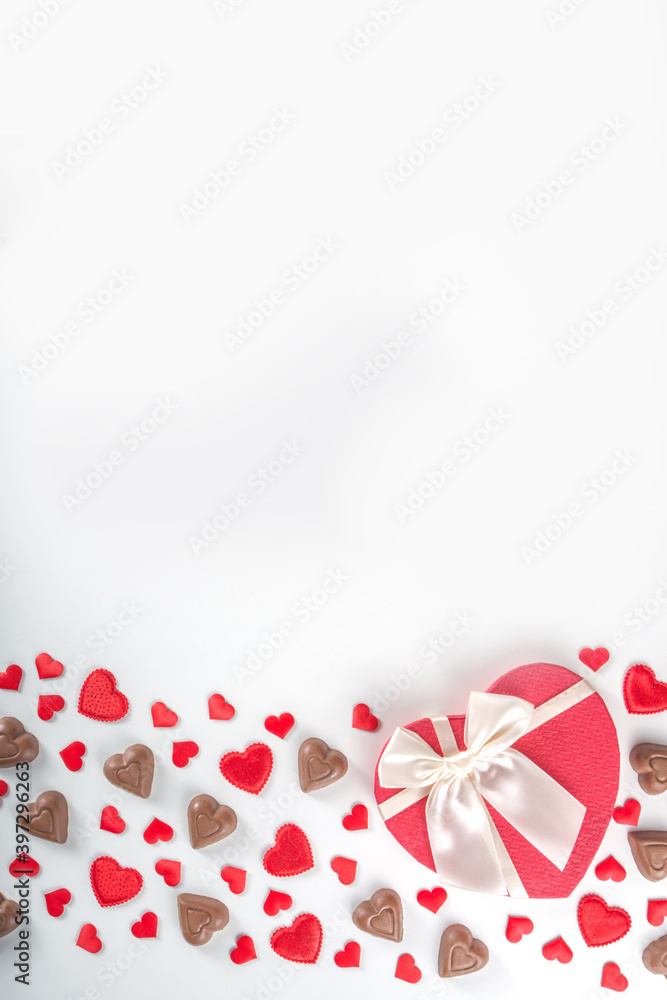 Red hearts, gift with ribbon and chocolates hearts flat lay, Valentine day and love background. Valentine's hearts ornament on white backdrop copy space top view