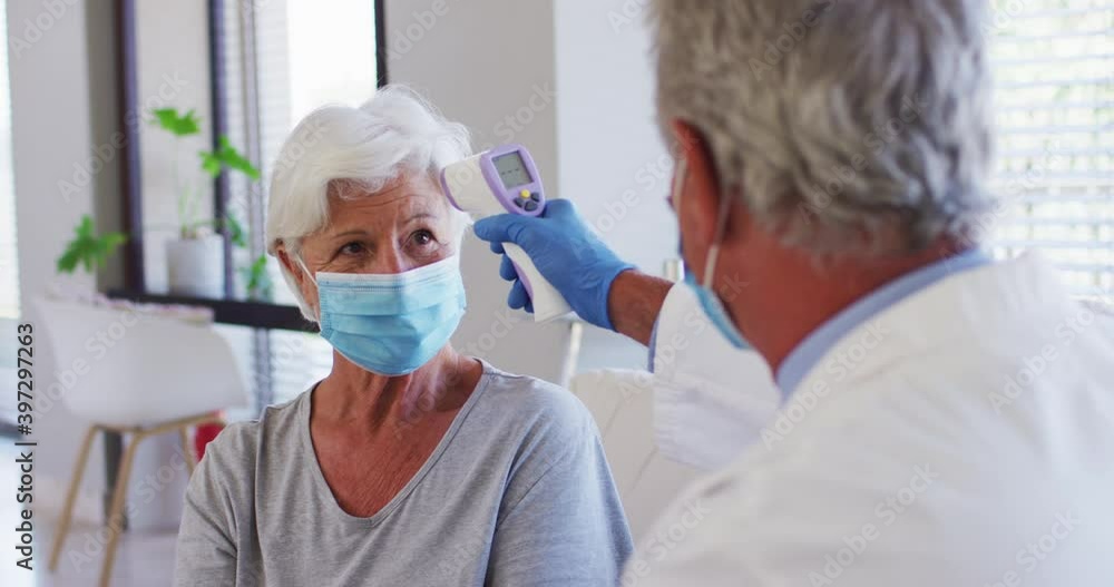 Male caucasian doctor measuring temperature of senior caucasian woman at hospital Male caucasian doctor measuring temperature of senior caucasian woman at hospital