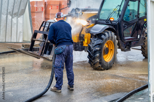 Worker washing construction machinery