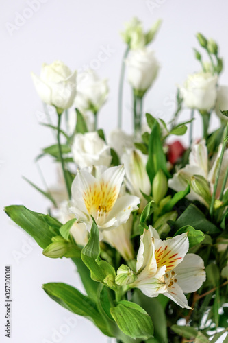 White alstroemerias of a bouquet close up. mas in a glass vase on a glass table. Beautiful flowers for women's day. A bouquet as a gift. White green bouquet.