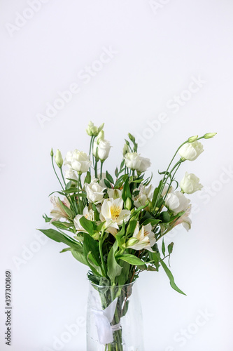 Bouquet of white alstroemerias and white eustomas in a glass vase. Beautiful flowers for women's day. A bouquet as a gift. White red green bouquet. 