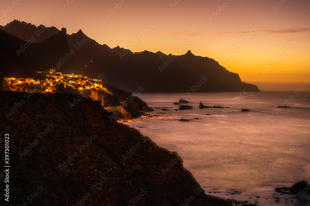 Fototapeta premium sunset at the coast of island tenerife with village at the mountain coast