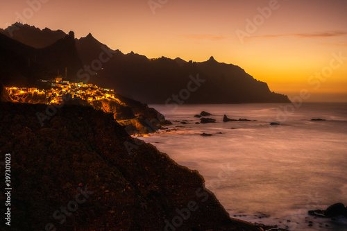 sunset at the coast of island tenerife with village at the mountain coast