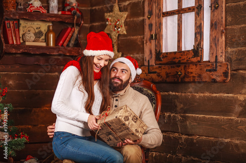 Happy young couple in santa hat at home at christmas with new year gifts