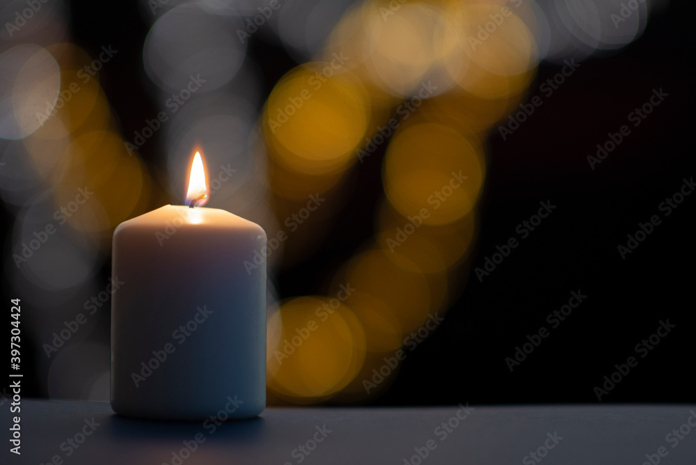 Burning candle on black background with bokeh. Christian christmas concept..