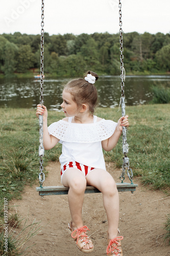 little, cute girl swings on a swing photo