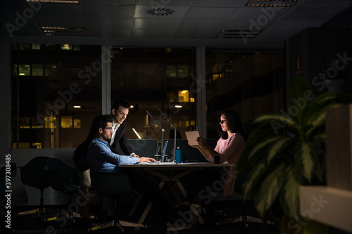 Cheerful young group of colleagues working late in office photo