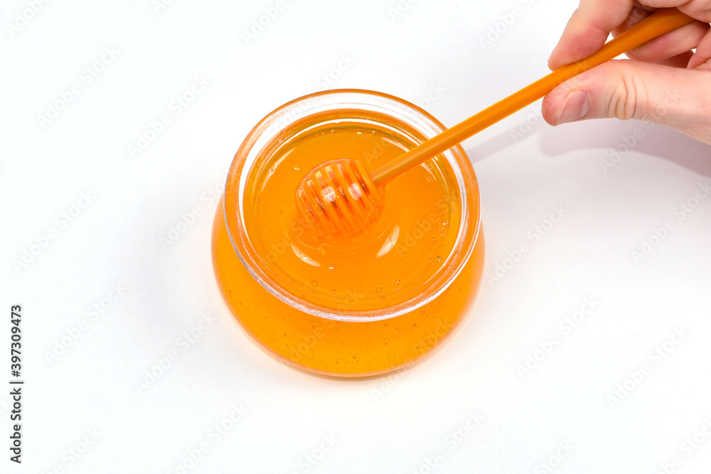 Close up hand holding dipper for honey, honey pouring into jar. Glass jar with honey. Close up hand holding dipper for honey, honey pouring into jar. Glass jar with honey.