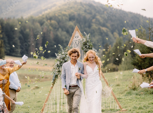 guests sprinkle leafs on just married couple at wedding ceremony photo