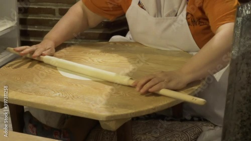 A woman is rolling the dough for baklava with rolling pin