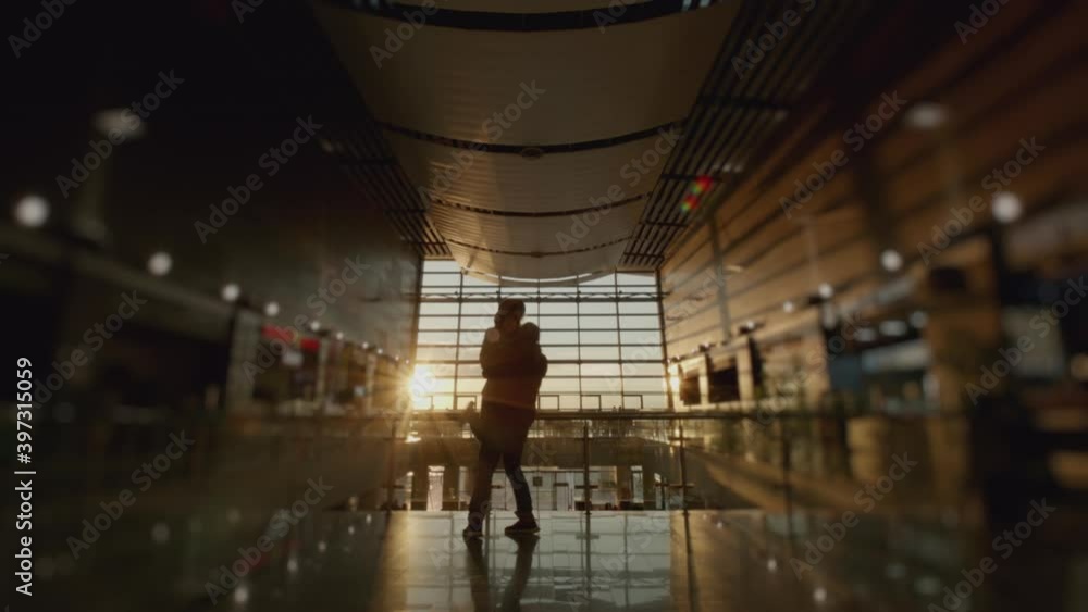Silhouette of man and a woman meeting in airport terminal after arrival. People hugging. Concept of travel, tourism and transport. Sunset panoramic window at background. 6k downscale 10 bit. Silhouette of man and a woman meeting in airport terminal after arrival. People hugging. Concept of travel, tourism and transport. Sunset panoramic window at background. 6k downscale 10 bit.