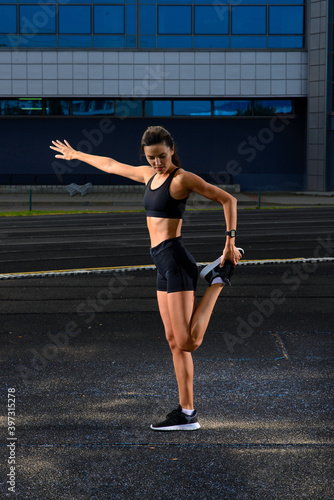 Healthy young woman warming up stretching her arms and looking away in the stadium outdoor.