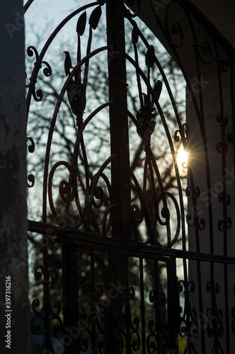 Sun shining through the bars of a wrought-iron gate photo