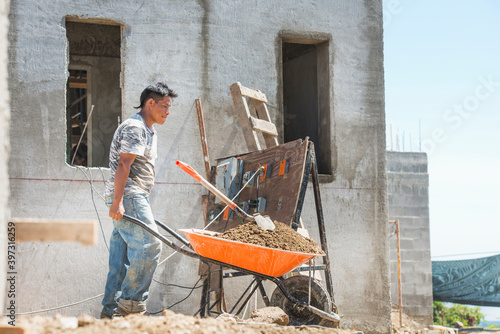 Hispanic construction worker pushing wheelbarrow at construction site photo